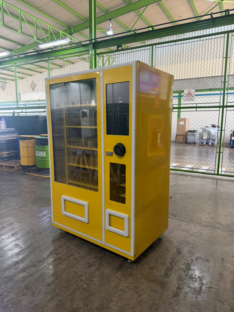 Máquina expendedora Modelo B en el galpón, junto a un cartel de la empresa